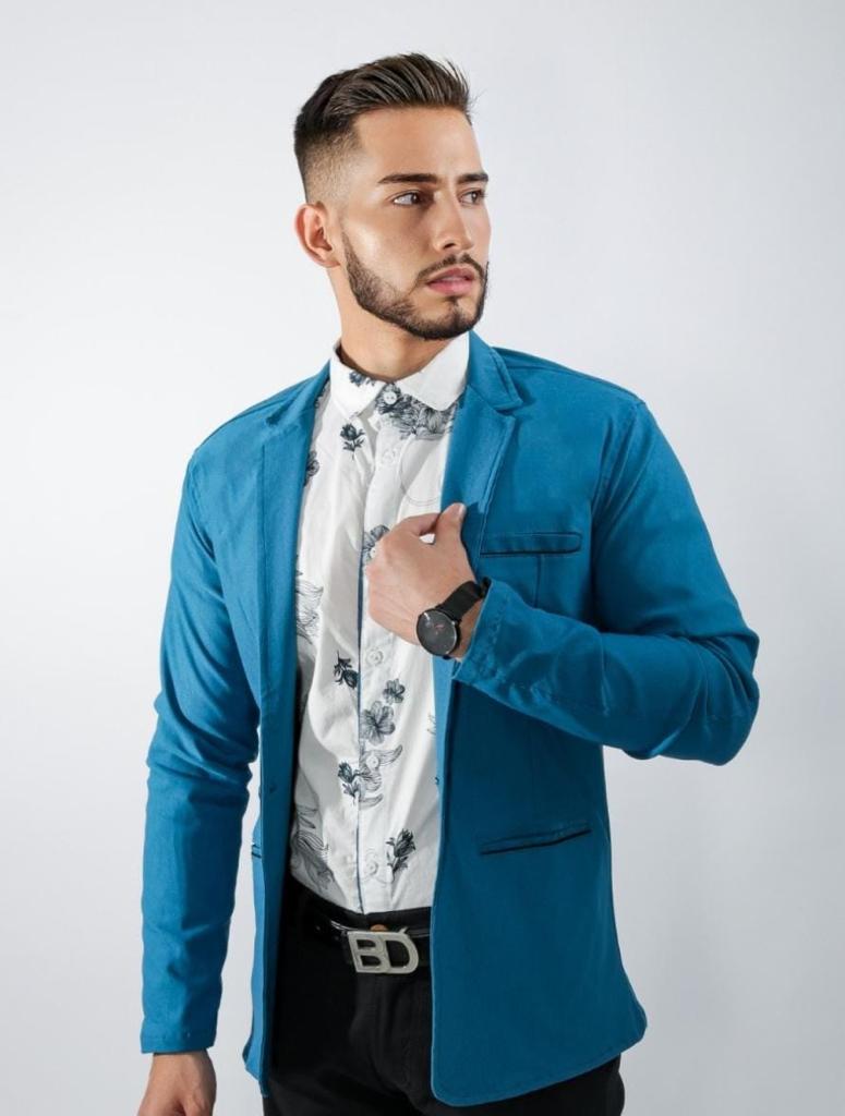 Hombre con blazer azul petróleo, camisa clara estampada y pantalón oscuro.